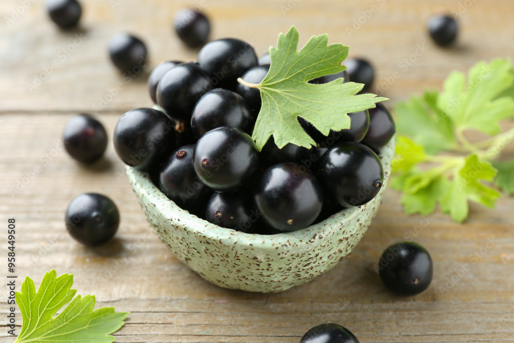 Fresh ripe black currant berries and leaves on wooden table, closeup Fresh ripe black currant berries and leaves on wooden table, closeup