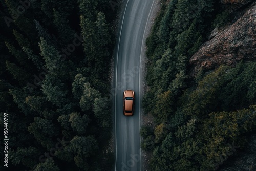 Aerial view of an orange car traveling down a winding road surrounded by dense trees, highlighting a peaceful and serene journey through a forested area in nature.