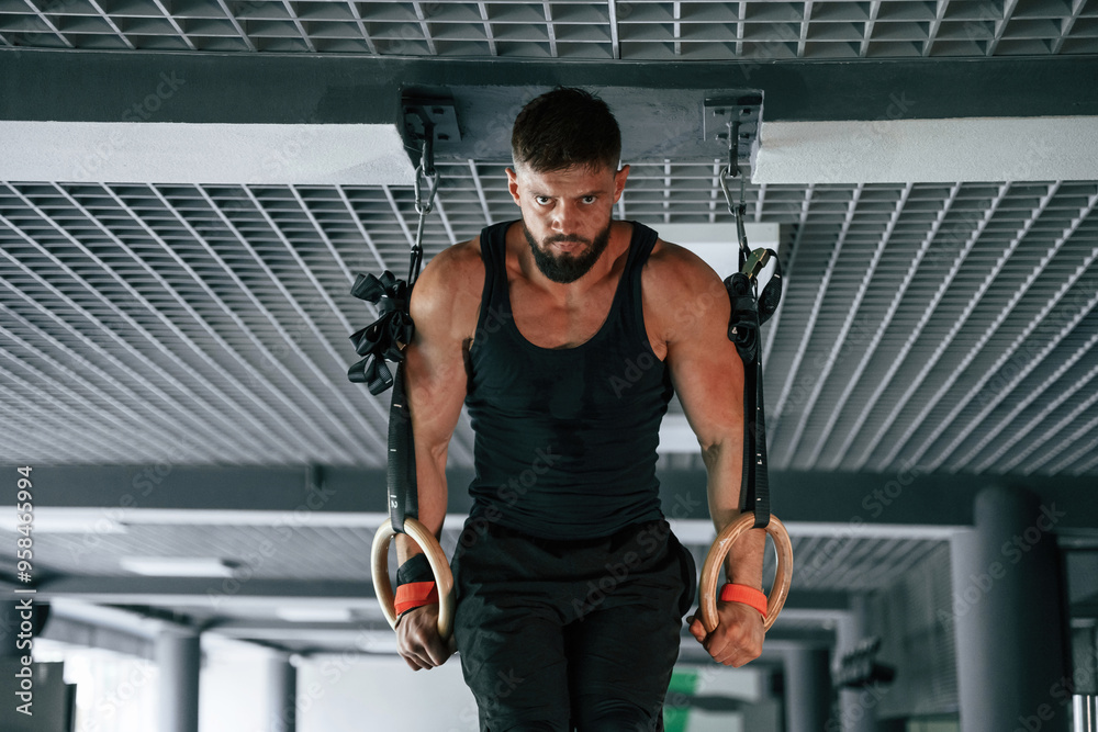 On the athletic rings. Strong muscular man is working out in the gym On the athletic rings. Strong muscular man is working out in the gym
