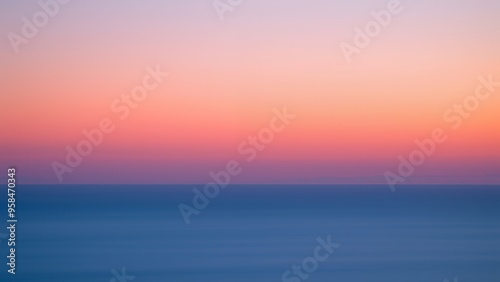 A peaceful, soft sunset over calm ocean water.