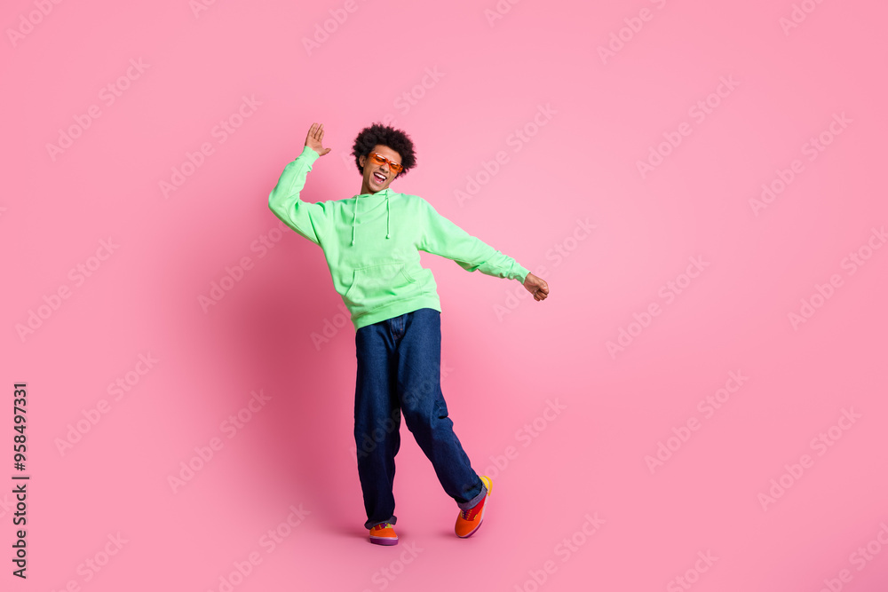 Full size photo of nice young man dancing wear green hoodie isolated on pink color background Full size photo of nice young man dancing wear green hoodie isolated on pink color background