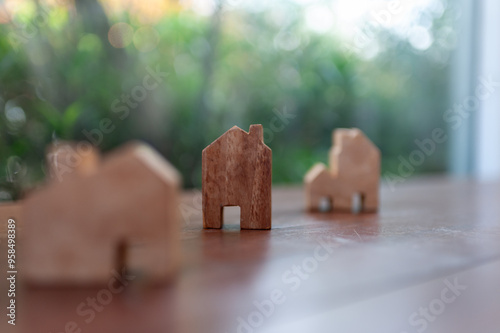 Wooden house models arranged on a table, symbolizing home, real estate, and architectural design against a blurred background. photo