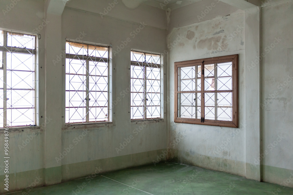 Obraz premium Spacious interior with weathered walls and large windows, providing natural light and an airy atmosphere.