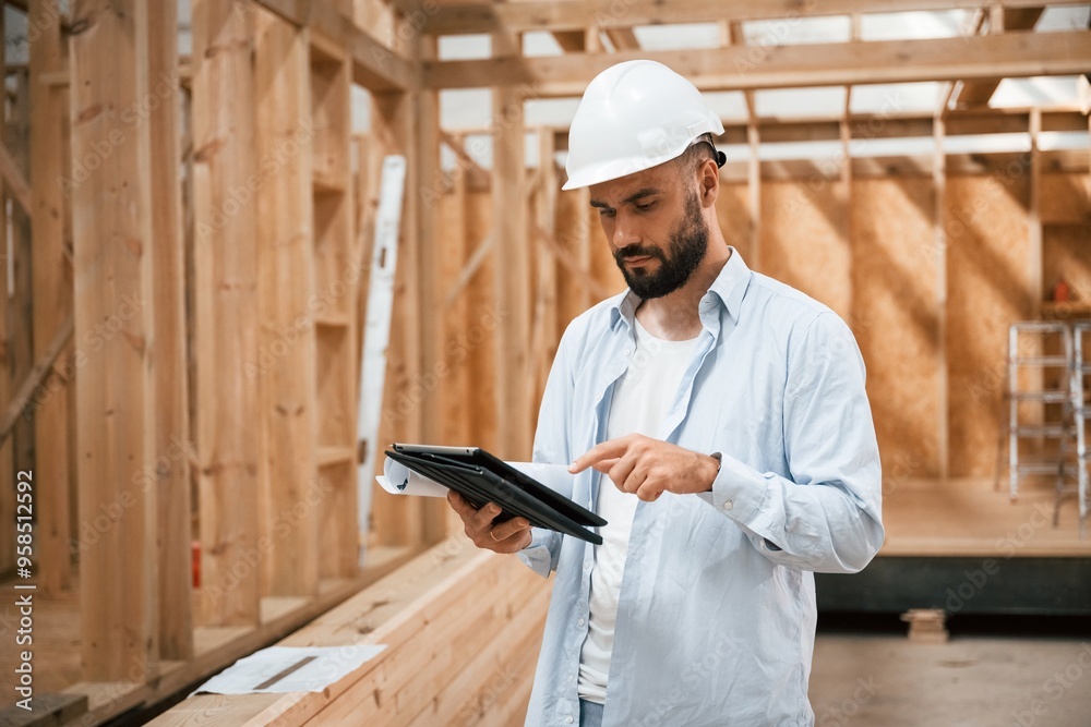 Digital tablet is in hands. Industrial worker in wooden warehouse