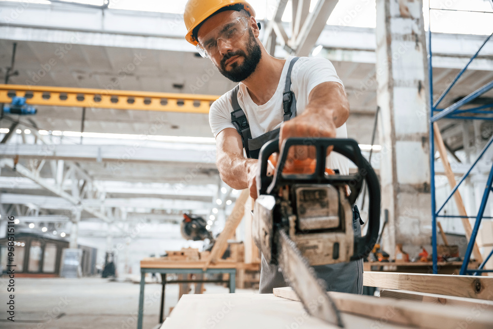 Saw in hands. Industrial worker in wooden warehouse Saw in hands. Industrial worker in wooden warehouse