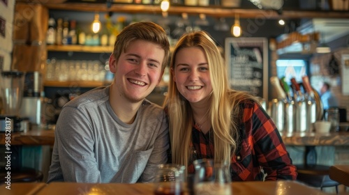 Photograph of a young couple smiling in a coffee shop, looking at the camera.