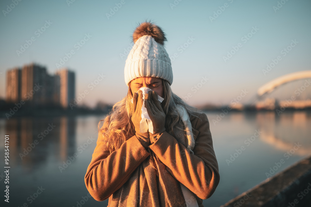 Woman in warm clothing blowing nose outdoor. Woman in warm clothing blowing nose outdoor.
