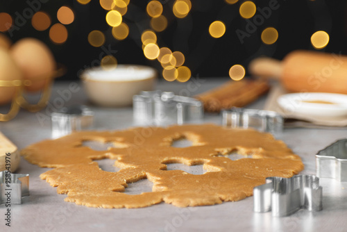 Raw dough and cookie cutters on grey table, closeup