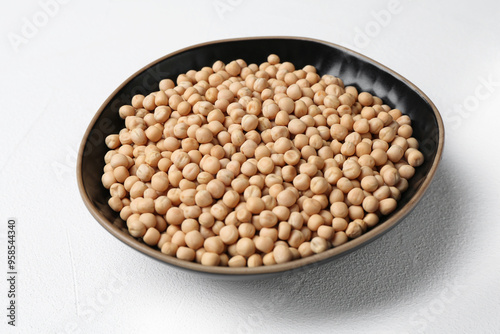 Dried peas in bowl on white textured table, closeup