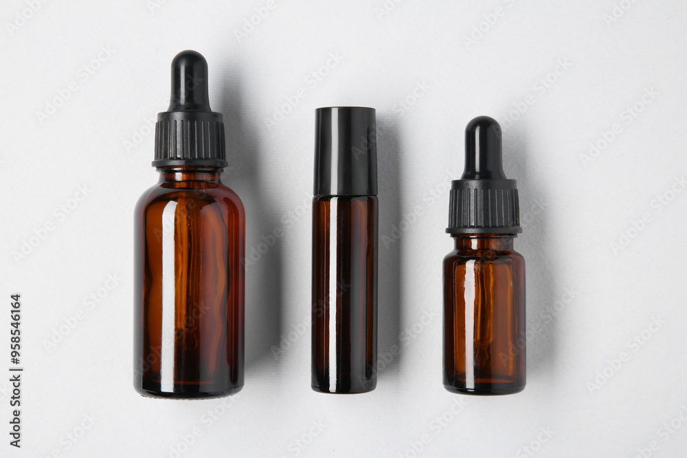 Essential oils in bottles on light background, flat lay Essential oils in bottles on light background, flat lay