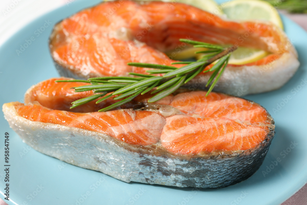 Tasty grilled salmon steaks and rosemary on light blue plate, closeup Tasty grilled salmon steaks and rosemary on light blue plate, closeup