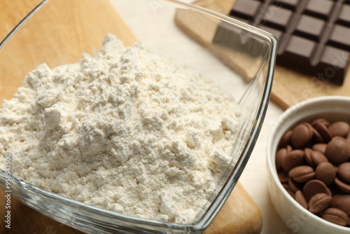 Flour in bowl and chocolate for making dough on light table, closeup