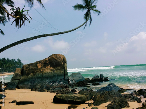 tropischer Strand mit Meer,  Wellen, Felsen und Palmen photo