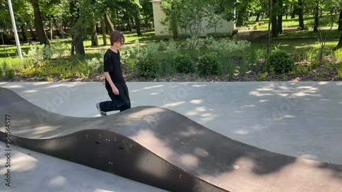 Young man practicing skateboarding tricks on a ramp in a skatepark, showcasing skill and balance in an active lifestyle photo