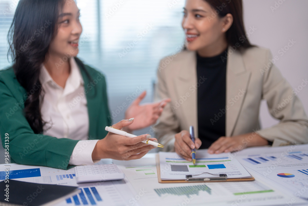 Two businesswomen having meeting and discussing new business project using graphs and charts Two businesswomen having meeting and discussing new business project using graphs and charts