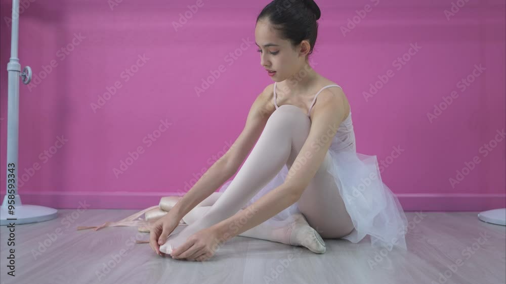 A girl ballet student, Wear ballet shoes on floor and prepare to practice ballet at home A girl ballet student, Wear ballet shoes on floor and prepare to practice ballet at home