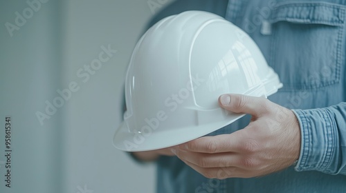 White hard hat held in hands, representing careful attention to safety on construction sites. A great choice for business, safety, or industrial visuals. photo