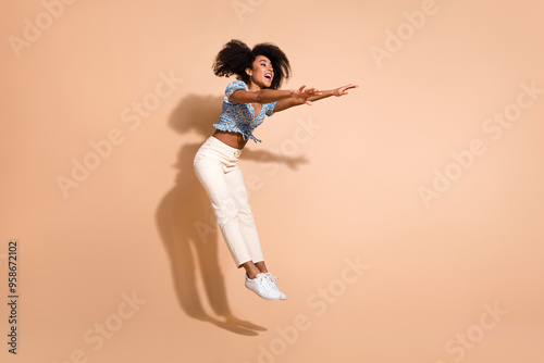 Full length photo of cheerful pretty lady dressed blue blouse jumping high empty space isolated beige color background photo