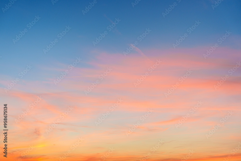 Obraz premium The sunset creates a stunning display in the sky, showcasing vibrant pink, orange, and blue hues. This breathtaking scene is perfect for capturing the beauty of nature at dusk.