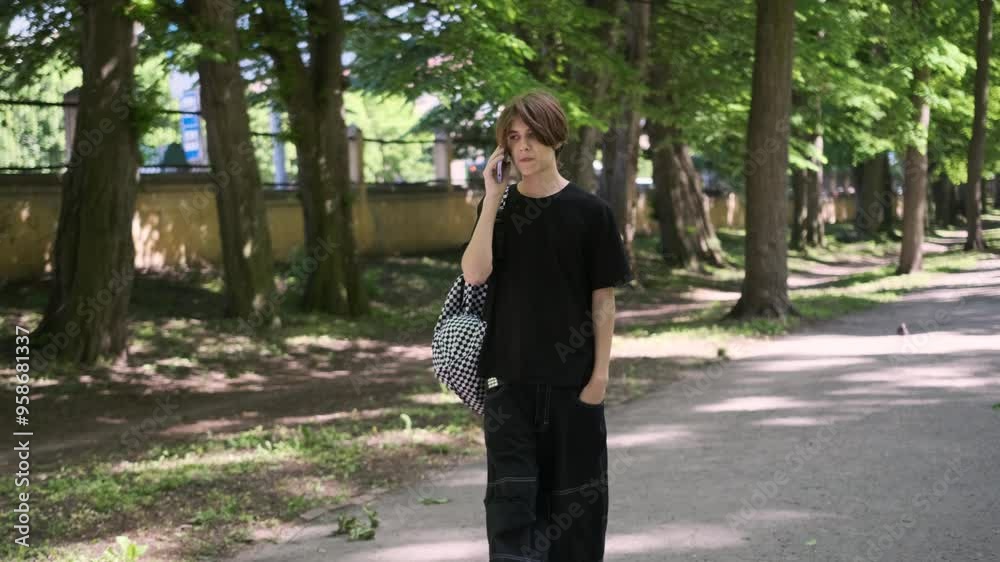Young man converses on the phone while strolling through a serene park, enjoying nature and the outdoors Young man converses on the phone while strolling through a serene park, enjoying nature and the outdoors