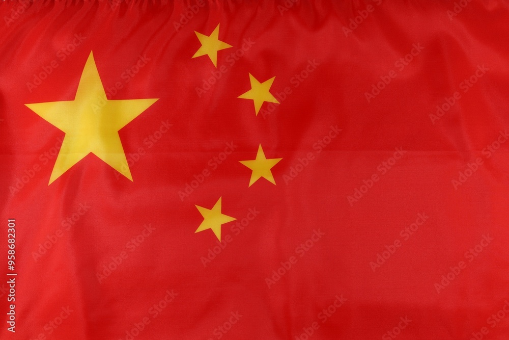 A close-up view of the national flag of China featuring a red background with a large yellow star and four smaller stars A close-up view of the national flag of China featuring a red background with a large yellow star and four smaller stars