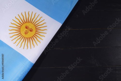 A close-up view of the Argentine flag draped across a dark wooden surface, showcasing its iconic sun emblem and blue and white stripes photo