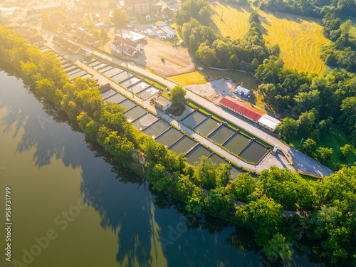 This aerial perspective captures intricate layout of fish farm pools in Trebon, Czechia, surrounded by lush greenery and rural landscapes. Nearby, agricultural fields enhance the serene environment. photo