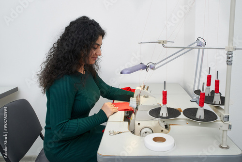 dressmaker using professional overlock sewing machine in workshop studio. Equipment for edging, hemming or seaming clothes at tailors shop photo