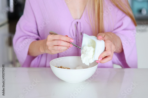 female hands putting yogurt with muesli healthy breakfast concept