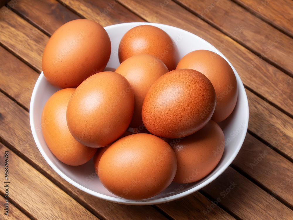 Huevos morenos de gallina en un bol sobre mesa de madera Huevos morenos de gallina en un bol sobre mesa de madera