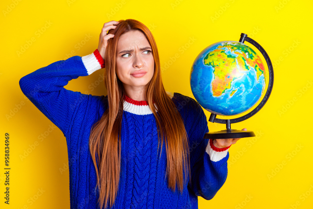 Fototapeta premium Photo portrait of pretty young girl look confused hold globe wear trendy blue knitwear outfit isolated on yellow color background