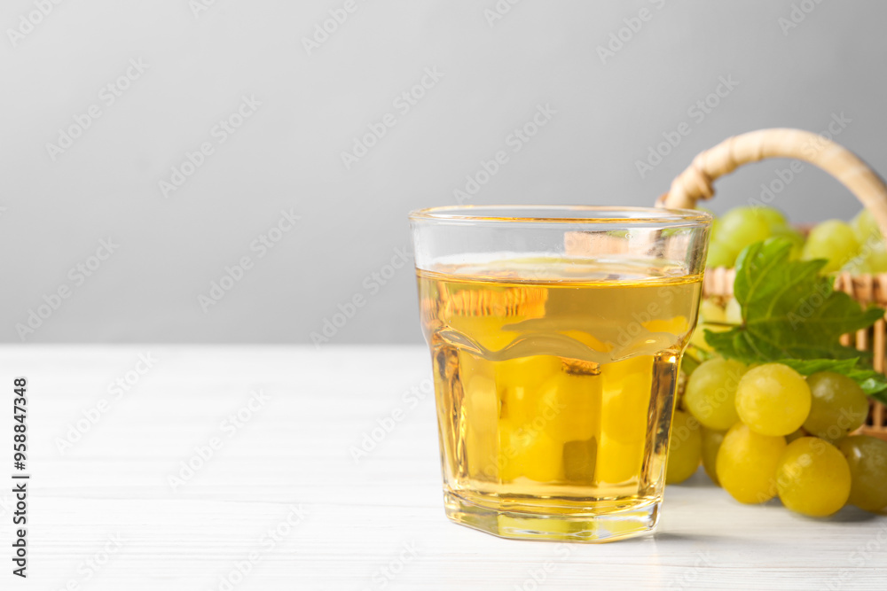Ripe grapes and glass of tasty juice on white wooden table. Space for text Ripe grapes and glass of tasty juice on white wooden table. Space for text