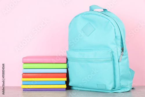 Backpack with different school stationery on light grey table against pink background