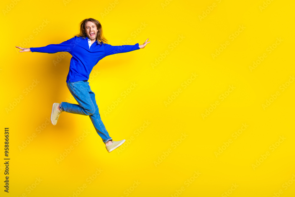 Photo of crazy cool positive man wear trendy blue clothes jump up run empty space isolated on yellow color background Photo of crazy cool positive man wear trendy blue clothes jump up run empty space isolated on yellow color background