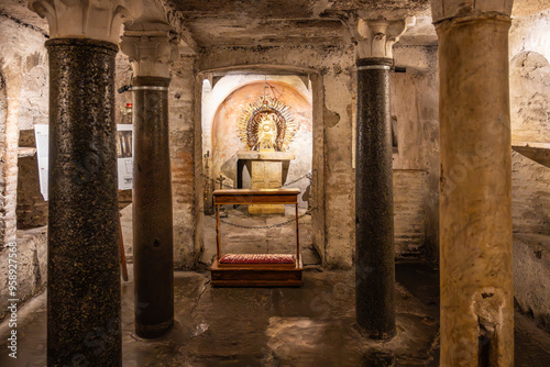 The crypt of the Basilica of Santa Maria in Cosmedin reveals a historic space adorned with pillars and an altar, showcasing intricate architecture from the eighth century in Rome, Italy.