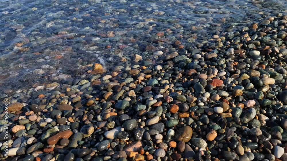 Waves splash on the coast with large colored stones. Pebble beach of the Black Sea in the city of Batumi. Travel to Georgia. Vacation at sea in Batumi. Waves splash on the coast with large colored stones. Pebble beach of the Black Sea in the city of Batumi. Travel to Georgia. Vacation at sea in Batumi.