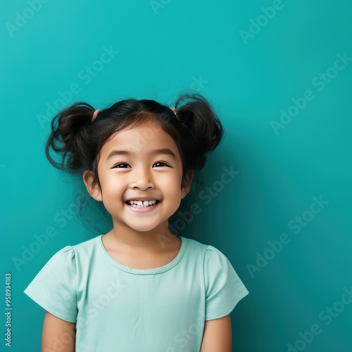 Teal background Happy Asian child Portrait of young beautiful Smiling child good mood Isolated on backdrop ethnic diversity equality acceptance concept 