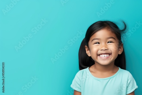 Teal background Happy Asian child Portrait of young beautiful Smiling child good mood Isolated on backdrop ethnic diversity equality acceptance concept 