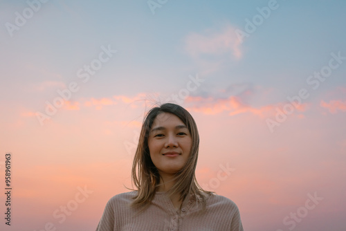 Portrait of asian woman standing still with colorful pastel sky background.