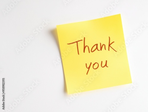 A yellow sticky note with Thank you written in simple handwriting, placed on a plain white background