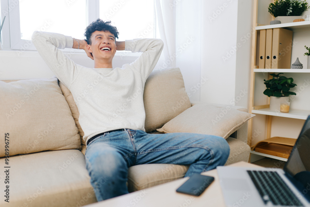 Relaxed man enjoying leisure time at home, smiling on couch in bright room Cozy atmosphere with soft colors creating a sense of comfort and relaxation