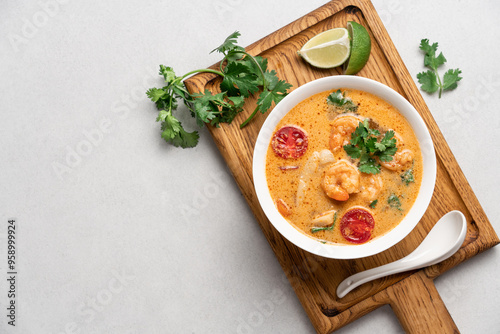Tom yum soup with shrimps in white bowl on light background with copy space. Popular traditional asian cuisine