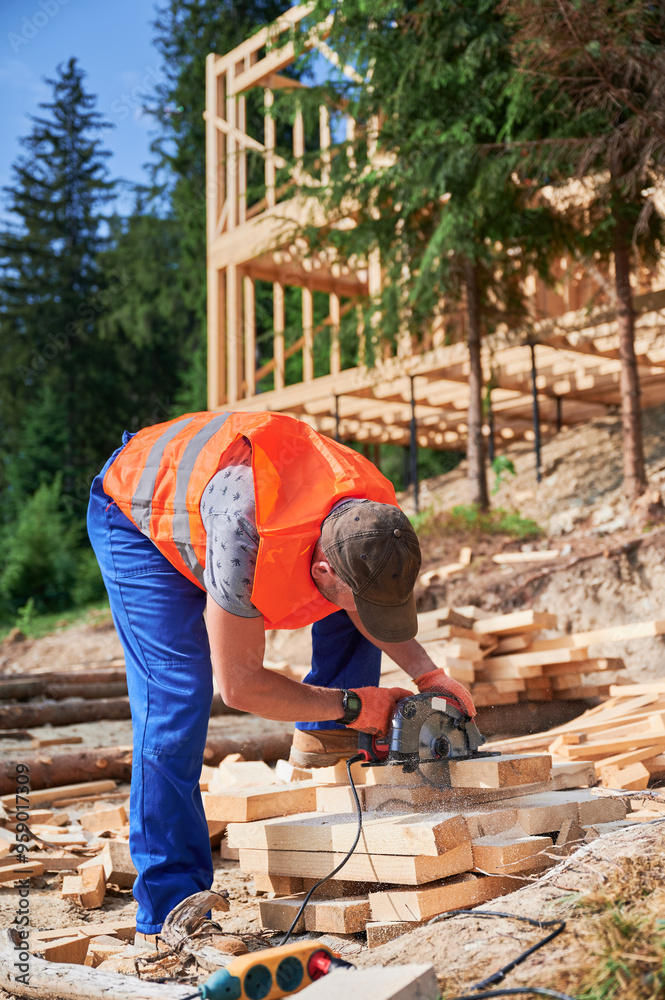 Carpenter using circular saw for cutting wooden plank. Man worker building wooden frame house. Concept of contemporary, eco-friendly building practices. Carpenter using circular saw for cutting wooden plank. Man worker building wooden frame house. Concept of contemporary, eco-friendly building practices.