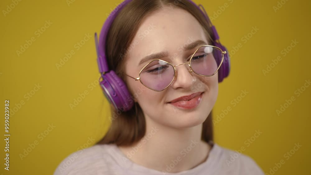 A stylish young woman wearing purple headphones and sunglasses, against a vibrant yellow background A stylish young woman wearing purple headphones and sunglasses, against a vibrant yellow background