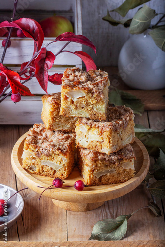 Obraz na płótnie Slices of Dutch apple cake with streusel on a wooden tray, apples and apple branches on a wooden background. w salonie