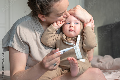 Mom measures body temperature baby by electronic thermometer. Sick child with high temperature. Children illness, clod and flue, runny nose, cough, disease, parent care