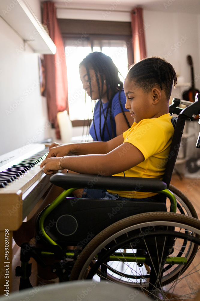 Vertical shot of two dark-skinned brothers playing an electronic piano in their living room. The disabled child in a wheelchair is in the foreground. Concept of young African people playing a piano. Vertical shot of two dark-skinned brothers playing an electronic piano in their living room. The disabled child in a wheelchair is in the foreground. Concept of young African people playing a piano.