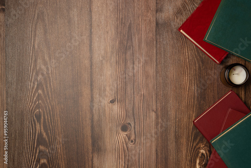 Books with candle on wooden background from above. Flat lay, top view.