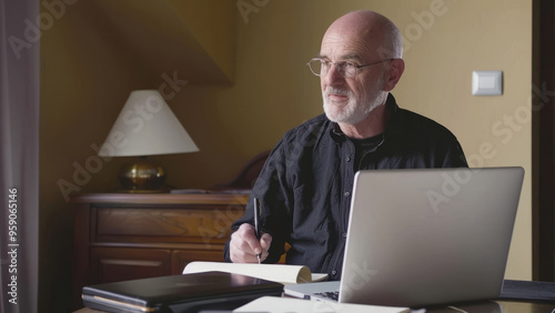 Focused man working on a laptop in a library with bookshelves behind him