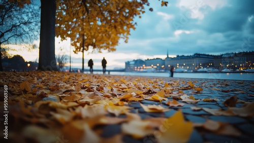 Autumn leaves scattered on a cobblestone path by the riverside at dusk